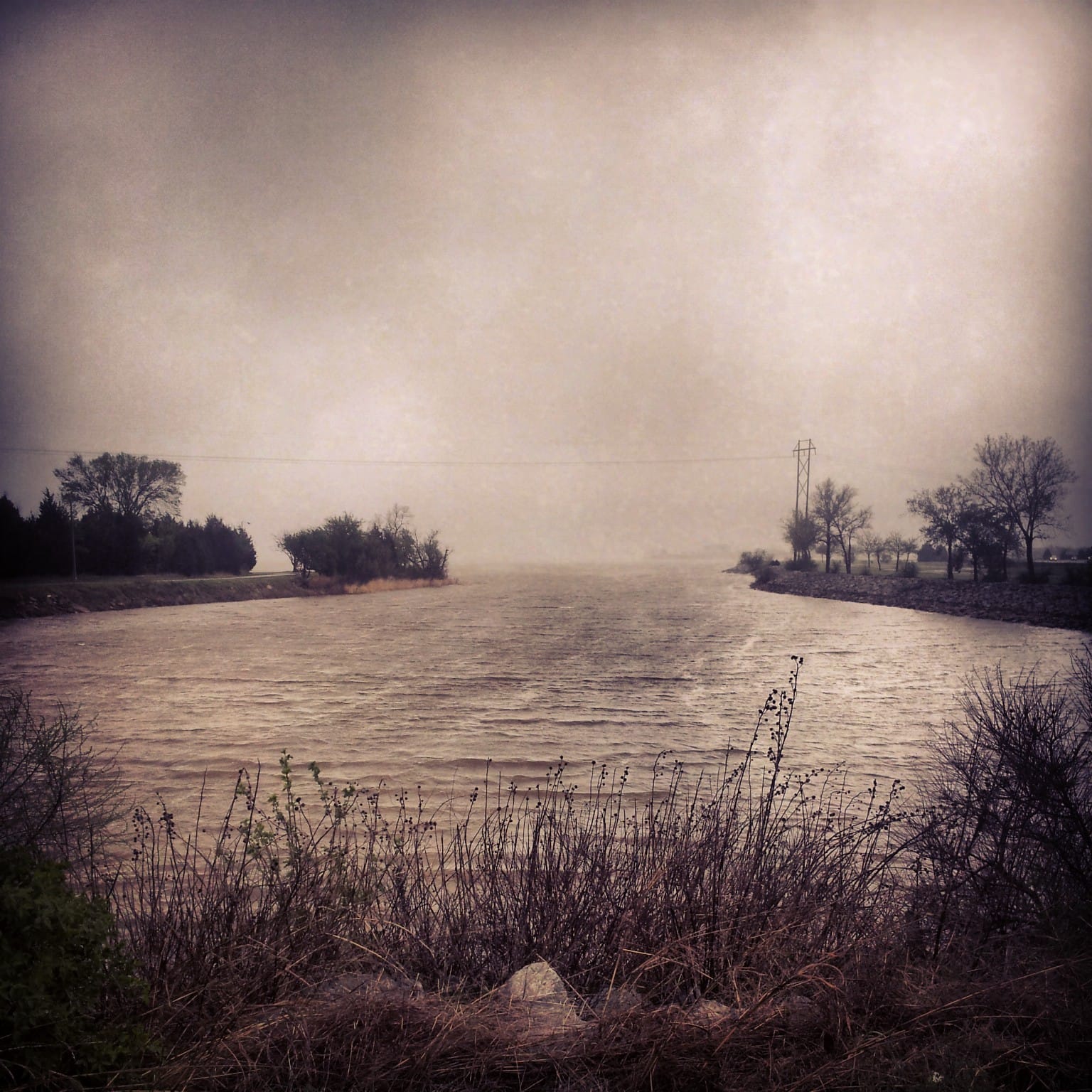 Faded color photo of Lake Hefner backed by clouds.