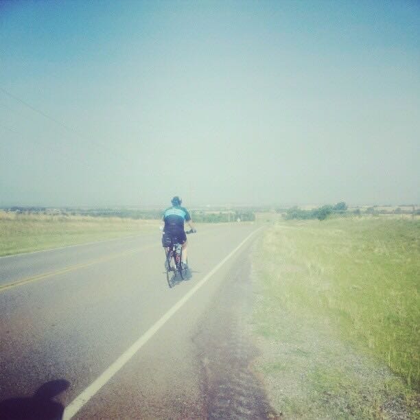 Faded color photo of cyclist riding towards a long downhill.