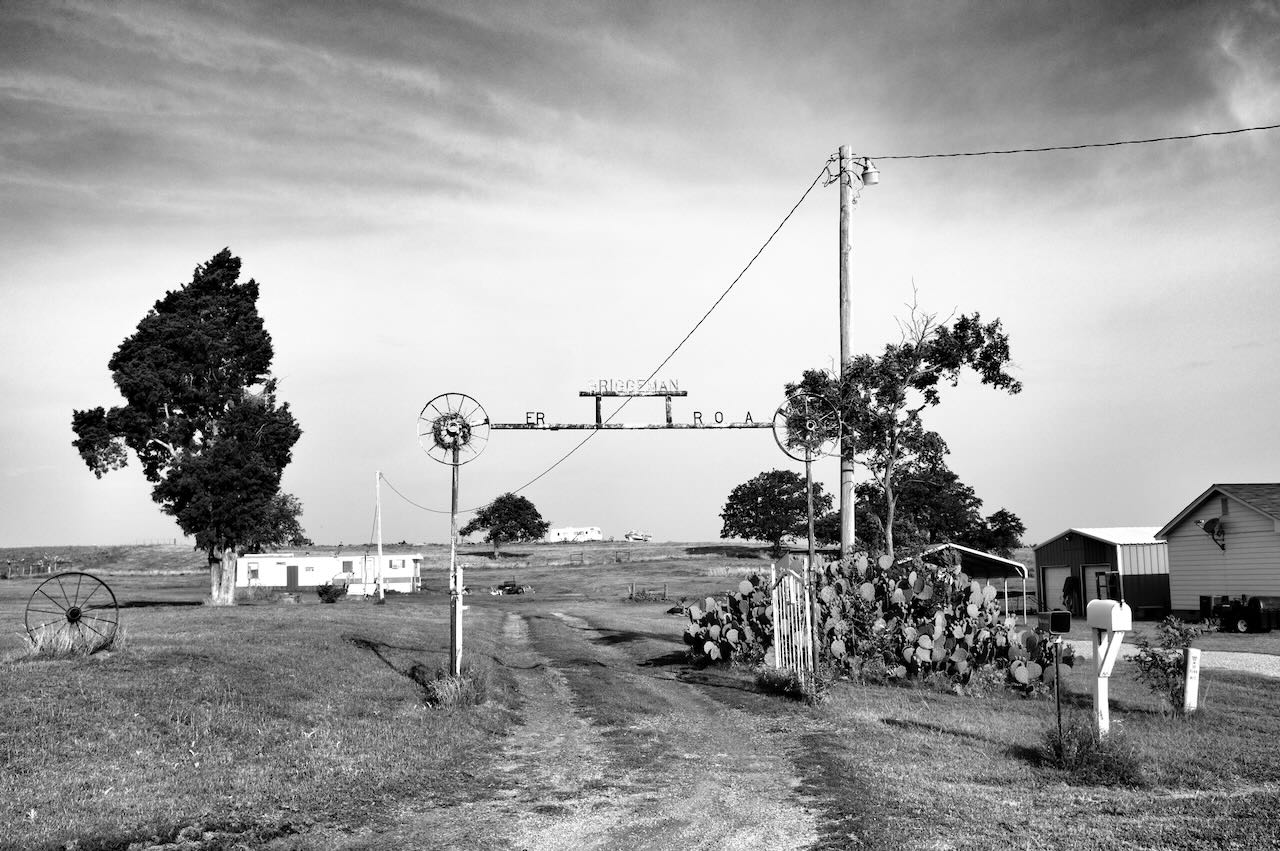 B&W photo of an old steel ranch gate and sign.