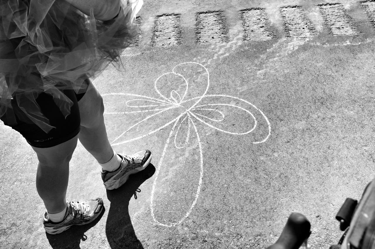 B&W photo of butterfly drawn in chalk on the road.