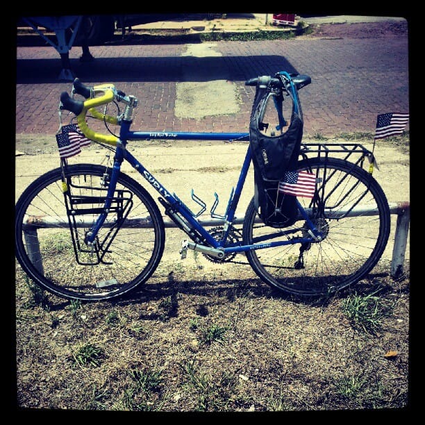 Color photo of a blue Surly bicycle decked out with flags.