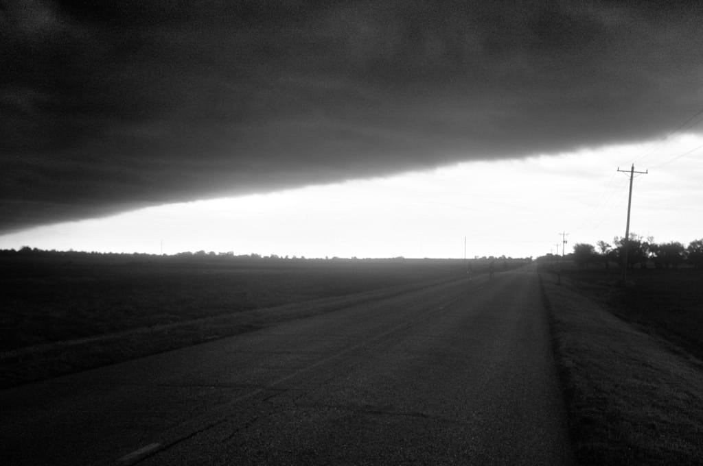 B&W picture of storms over a road.