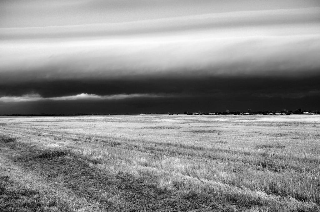 B&W picture of storms over a wheat field.