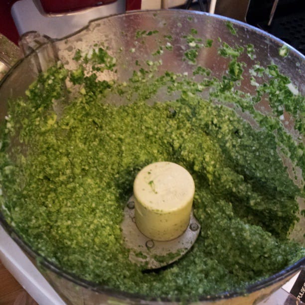 Color photo of a homemade pesto in a food processor.