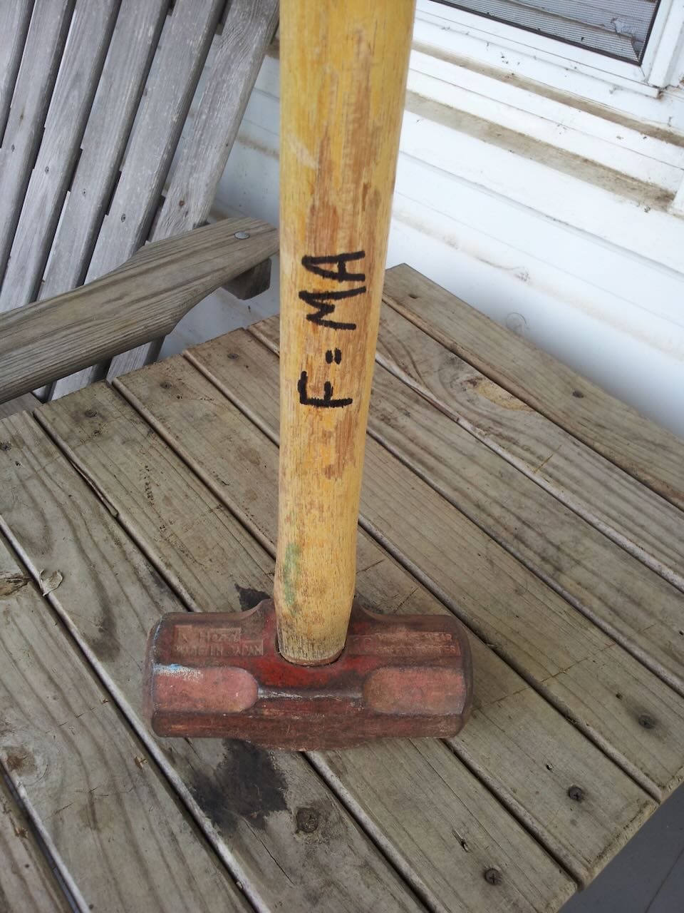 Color photo of a sledgehamer with F=MA written on it.