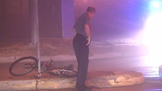 Color photo of police next to damaged bicycle.