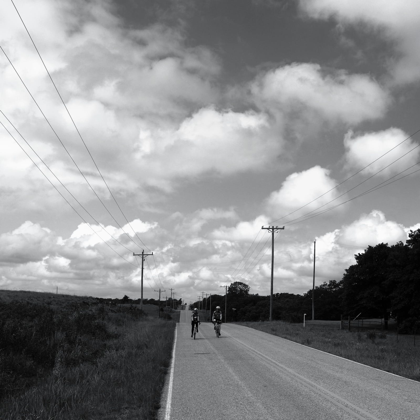 B&W photo of cyclists riding in the country.